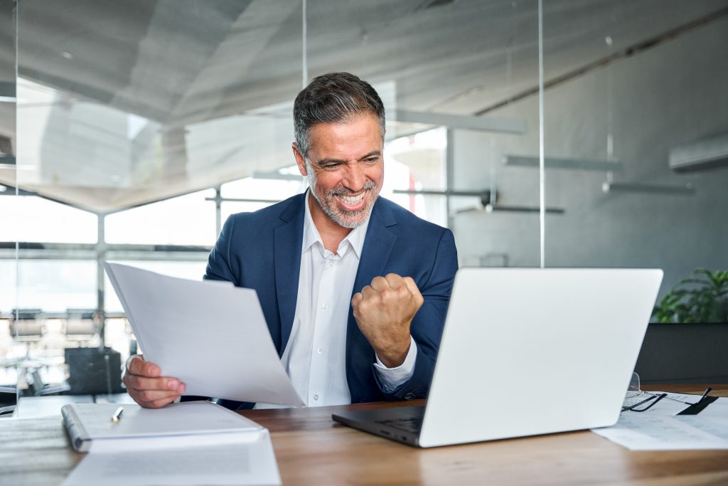Man celebrating while looking at laptop